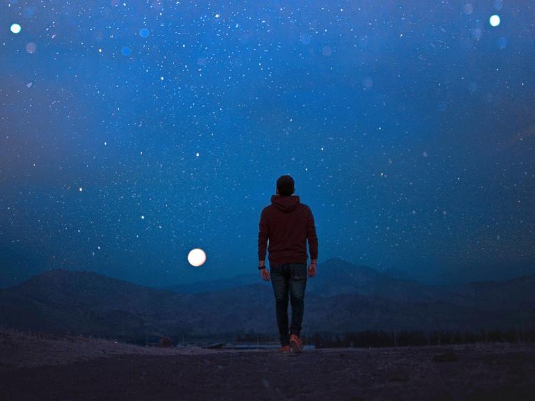 Ein neues humanes Wesen soll den Planeten wiederbesiedeln. Zu sehen: Ein Mann, mit dem Rücken zur Kamera, geht im Dunkeln in einer einsamen Landschaft dem Vollmond entgegen.