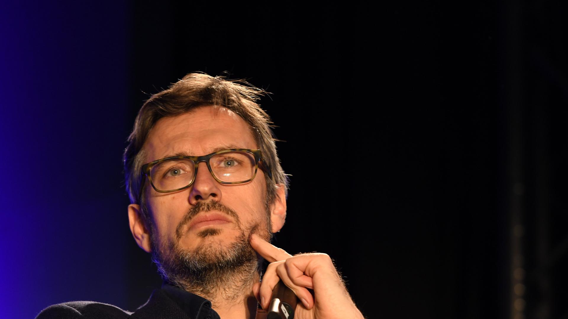 Der Produzent Jörg Winger blickt nach oben und drückt mit einem Finger der linken Hand in seine linke Wange Der Produzent Jörg Winger blickt nach oben und drückt mit einem Finger der linken Hand in seine linke Wange
