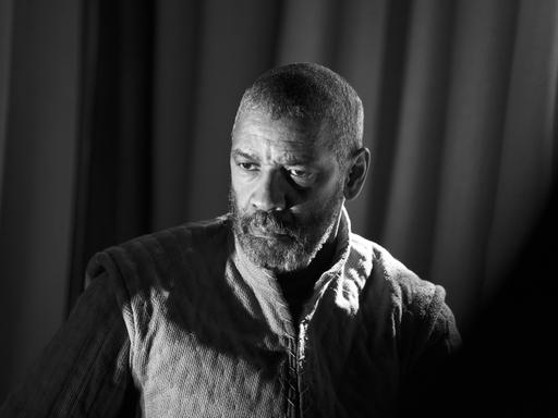 Der Schauspieler Denzel Washington spielt Macbeth, sein Gesicht ist im Halbschatten, er blickt nach links. Die Aufnahme ist in Schwarzweiß. 