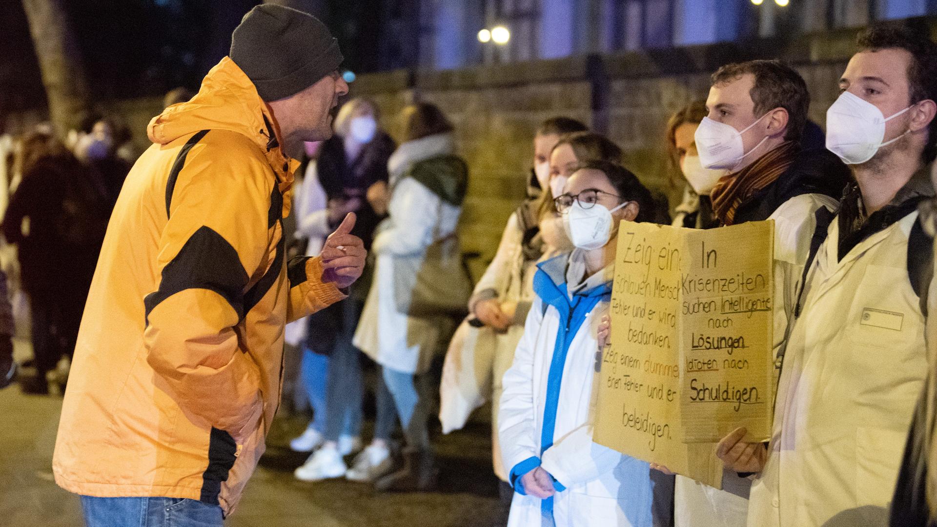 Ein Teilnehmer (l) einer als "Spaziergang" deklarierten Demonstration von Impfgegnern und Kritikern der Corona-Maßnahmen steht vor dem Universitätsklinikum Dresden vor zahlreichen Gegendemonstranten. Ein Teilnehmer (l) einer als "Spaziergang" deklarierten Demonstration von Impfgegnern und Kritikern der Corona-Maßnahmen steht vor dem Universitätsklinikum Dresden vor zahlreichen Gegendemonstranten.