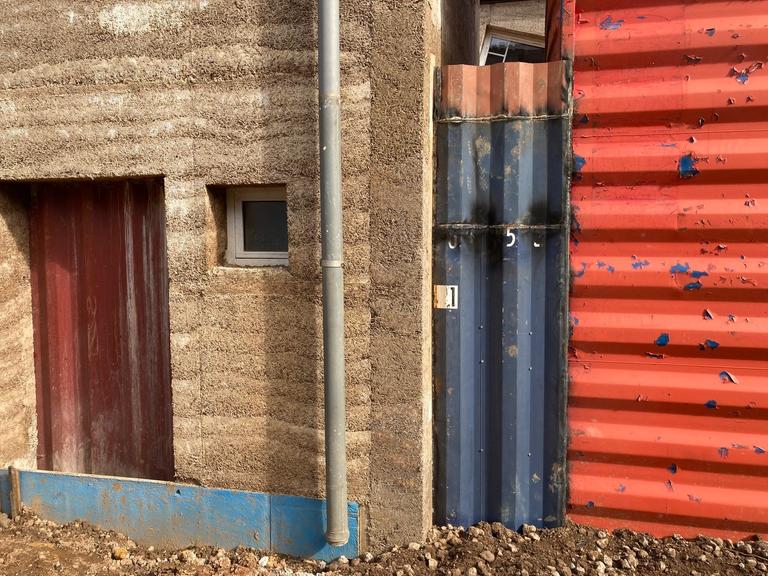 Blick auf ein Gebäude mit Seecontainer und Miscanthusgras-Isolierung