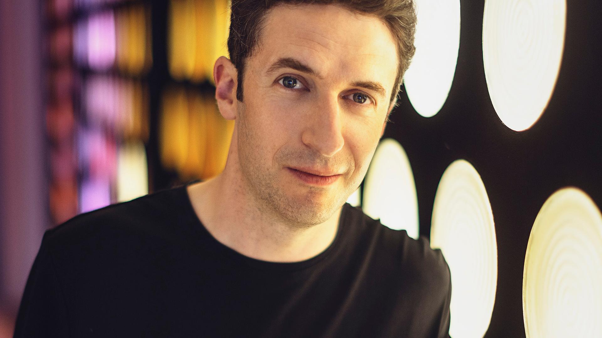 Noah Bendix-Balgley steht vor den runden zum Teil bunten Fenstern im Foyer der Berliner Philharmonie. Noah Bendix-Balgley steht vor den runden zum Teil bunten Fenstern im Foyer der Berliner Philharmonie.