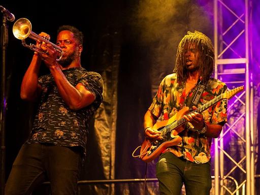 Gitarrist und Trompete-Spieler der Band Ogún Afrobeat auf der Bühne