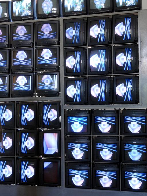 In der Bauhaus-Universität in Weimar betrachtet eine junge Frau im Jahr 2005 die Videowand "Internet Dream" von Nam June Paik. Die Wand besteht aus 52 Monitoren, die sowohl unterschiedliche Einzelbilder als auch ein großes Ganzes zeigen. 