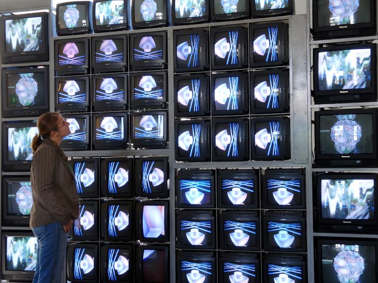 In der Bauhaus-Universität in Weimar betrachtet eine junge Frau im Jahr 2005 die Videowand "Internet Dream" von Nam June Paik. Die Wand besteht aus 52 Monitoren, die sowohl unterschiedliche Einzelbilder als auch ein großes Ganzes zeigen. 