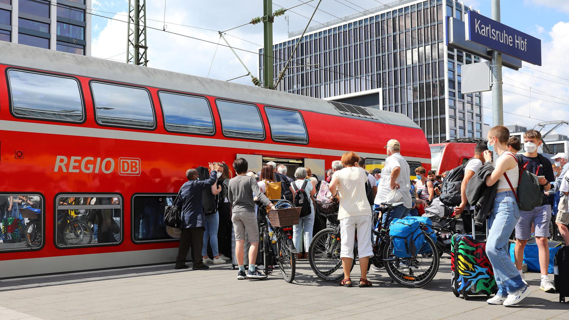 Fahrgäste warten in einer Schlange am Bahnsteig des Karlsruher Hauptbahnhofs auf den Einstieg in den Regionalexpress.