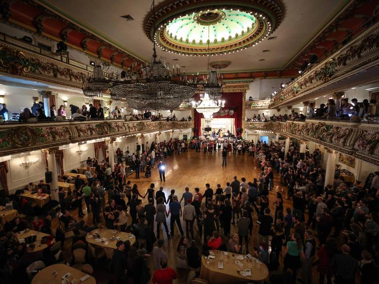 Viele Menschen bilden in der Grand Prospect Hall in New York, USA, einen Tanzkreis.