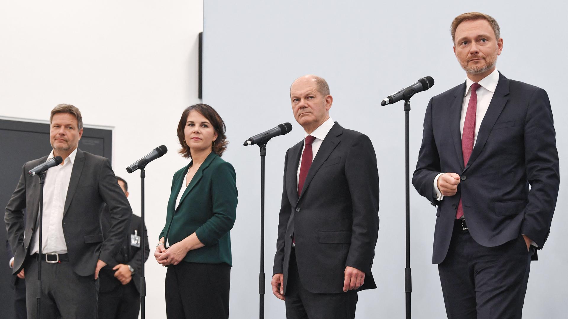 Robert Habeck, Annalena Baerbock, Olaf Scholz und Christian Lindner stehen während einer Pressekonferenz am Mikrofon. Robert Habeck, Annalena Baerbock, Olaf Scholz und Christian Lindner stehen während einer Pressekonferenz am Mikrofon.