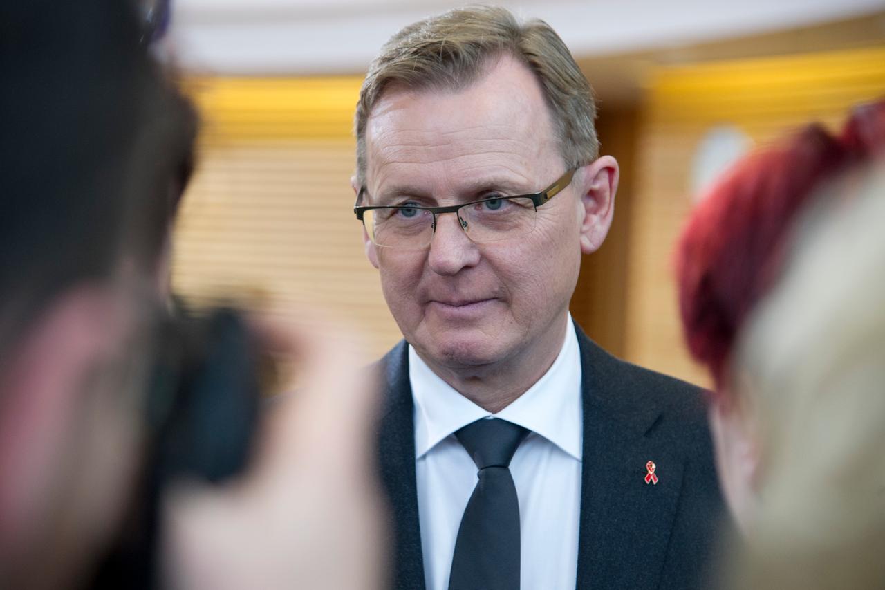 Bodo Ramelow schaut in eine Kamera, Hinterkopf eines anderen Fotografen und dessen Kamera sind im Vordergrund unscharf zu erkennen, rechts ist ein weiterer Kopf. Bodo Ramelow schaut in eine Kamera, Hinterkopf eines anderen Fotografen und dessen Kamera sind im Vordergrund unscharf zu erkennen, rechts ist ein weiterer Kopf.