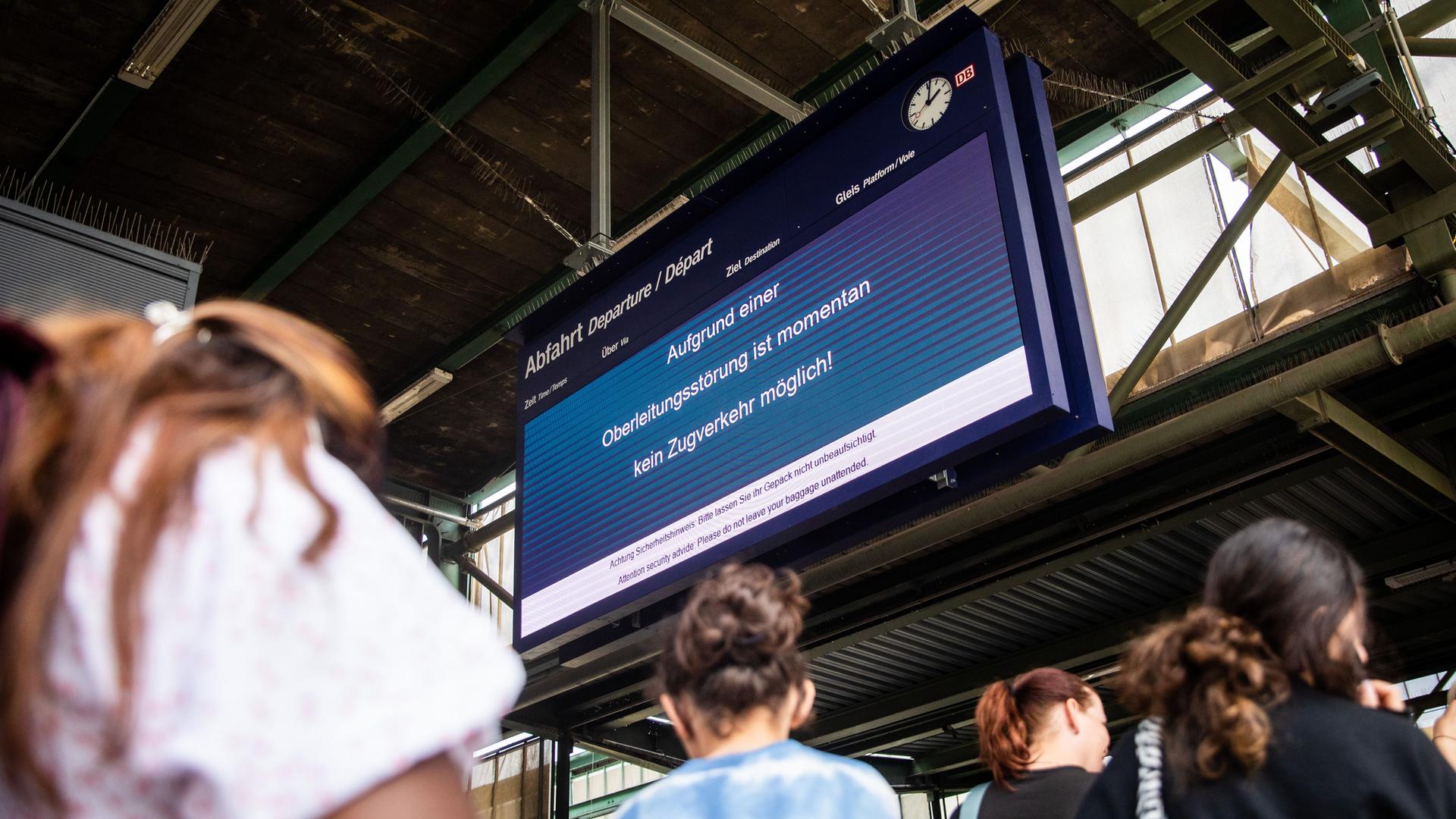 Während Fahrgäste in der Schlange zum DB Infoschalter anstehen, informiert eine Anzeigetafel im Stuttgarter Hauptbahnhof die Fahrgäste darüber, dass der Zugverkehr wegen eines Oberleitungsschadens aktuell nicht möglich ist. Während Fahrgäste in der Schlange zum DB Infoschalter anstehen, informiert eine Anzeigetafel im Stuttgarter Hauptbahnhof die Fahrgäste darüber, dass der Zugverkehr wegen eines Oberleitungsschadens aktuell nicht möglich ist.