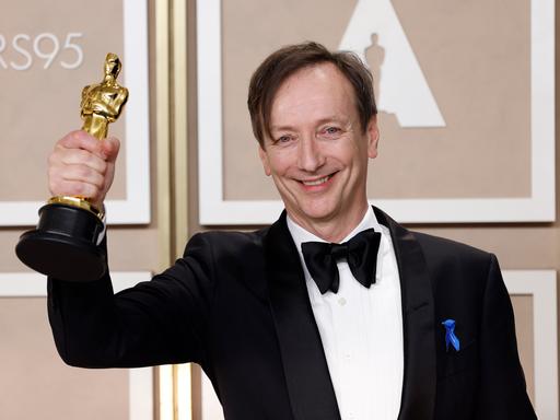 Der Komponist Volker Bertelmann hält die Oscar-Trophäe in der Hand. 