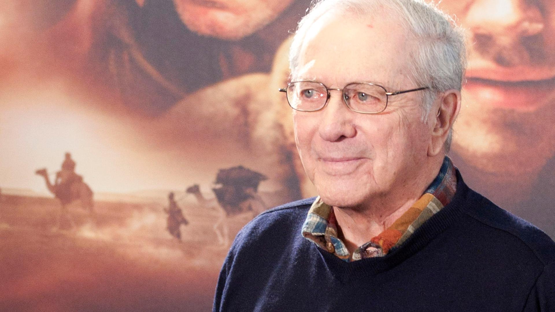 Der Schriftsteller Noah Gordon steht vor einer Werbewand des Films "Der Medicus". Er lächelt. Der Schriftsteller Noah Gordon steht vor einer Werbewand des Films "Der Medicus". Er lächelt.
