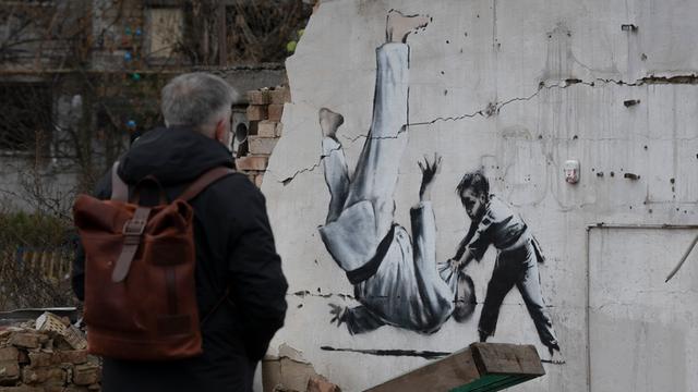 Ein Mann betrachtet in der Ukraine ein Kunstwerk des britischen Street-Art-Künstlers Banksy.