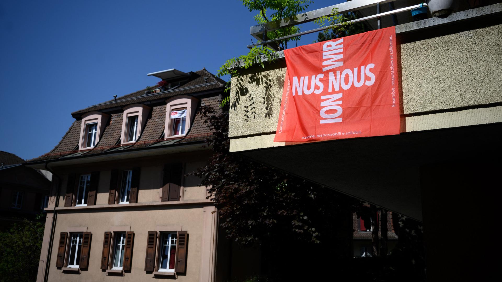 Flagge mit dem Schweizer Kreuz, das aus dem Wort "Wir" in den vier Schweizer Landessprachen gebildet wird (Deutsch: Wir, Französisch: Nous, Italienisch: Noi und Rätoromanisch: Nus) Flagge mit dem Schweizer Kreuz, das aus dem Wort "Wir" in den vier Schweizer Landessprachen gebildet wird (Deutsch: Wir, Französisch: Nous, Italienisch: Noi und Rätoromanisch: Nus)