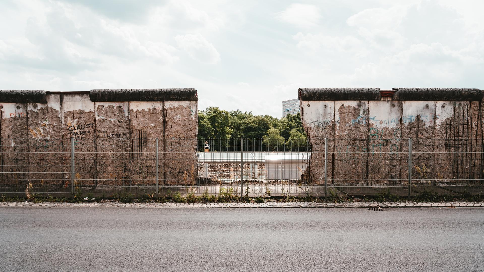 Die Berliner Mauer in der Niederkirchnerstraße 1 im Jahr 2019. In der Mitte ist ein großes Loch, durch das man hindurchsehen kann. Die Berliner Mauer in der Niederkirchnerstraße 1 im Jahr 2019. In der Mitte ist ein großes Loch, durch das man hindurchsehen kann.