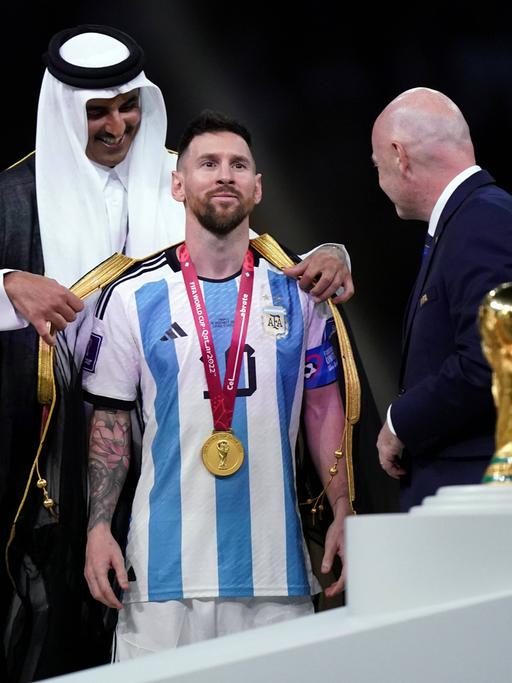 Der Emir von Katar überreicht Lionel Messi im Beisein von FIFA-Präsident Gianni Infantino einen Bischt.