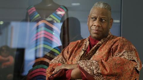 Andre Leon Talley in einem Kaftan in afrikanischem Design vor einer Modepuppe mit gestreiftem Kleid.