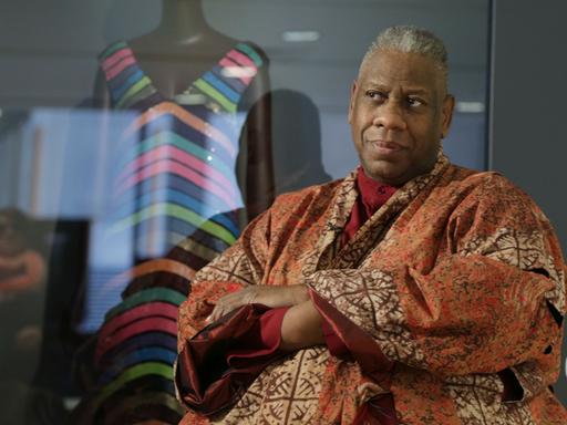 Andre Leon Talley in einem Kaftan in afrikanischem Design vor einer Modepuppe mit gestreiftem Kleid.