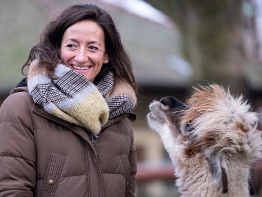 Das Bild zeigt die lächelnde Christina Geiger in einer Aussenaufnahme mit einem Zootier.