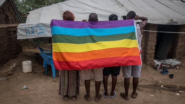 Das Foto zeigt Menschen aus Uganda, die nach Kenia geflüchtet sind. Sie halten eine Regen-Bogen-Fahne hoch.