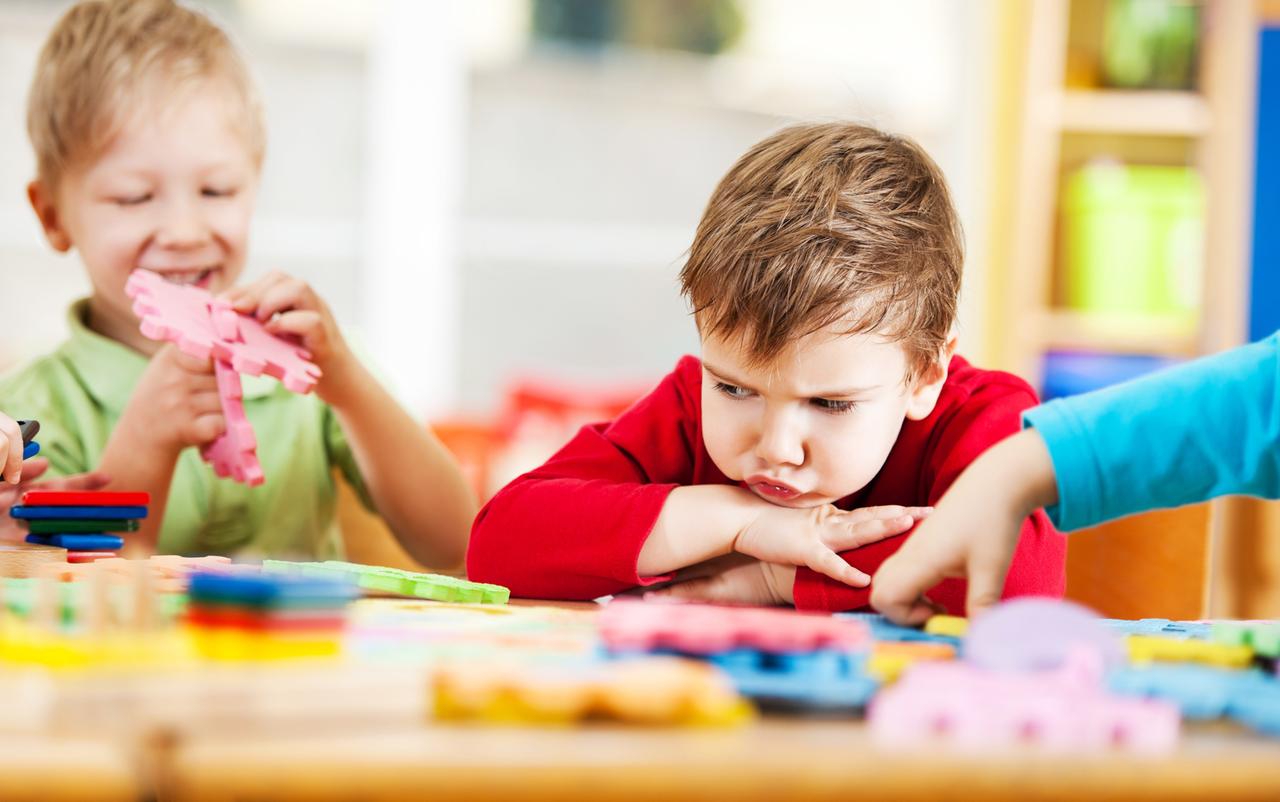 Ein kleiner Junge im Kindergarten schaut mit frustriertem Blick auf sein Puzzle. Ein kleiner Junge im Kindergarten schaut mit frustriertem Blick auf sein Puzzle.