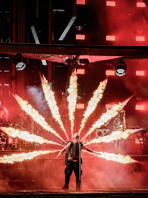 Rammstein-Sänger Till Lindemann ist von Feuerfontänen umgeben, die sternförmig aus einem Kasten auf seinem Rücken schießen.