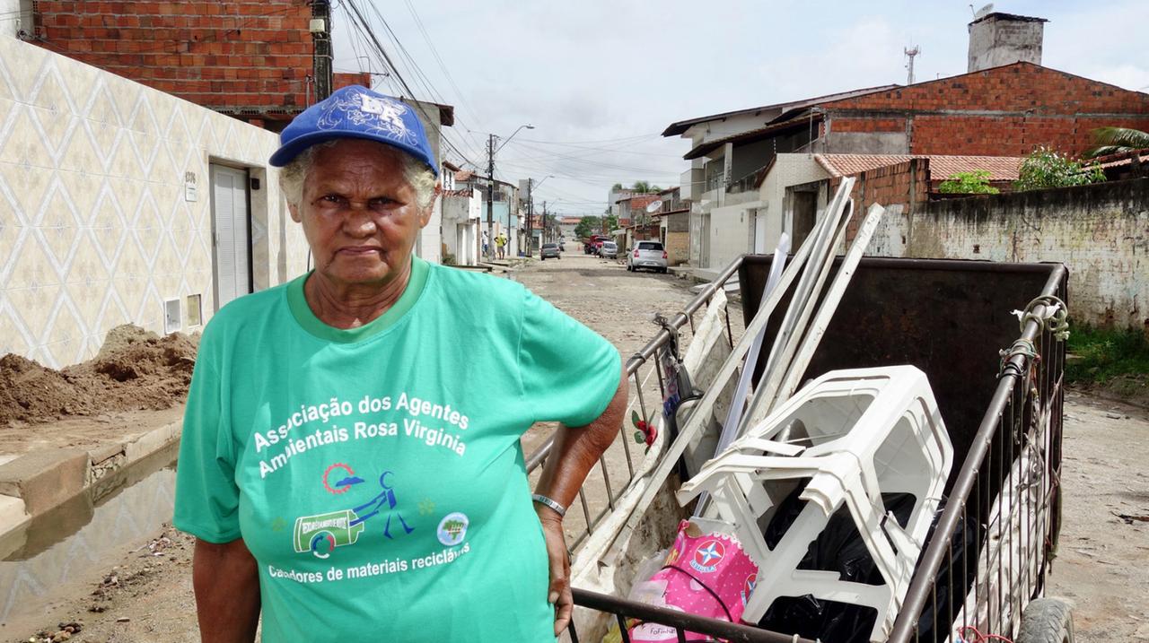 Eine ältere Frau mit einer blauen Kappe und einem grünen T-Shirt in einem brasilianischen Dorf auf der Straße.