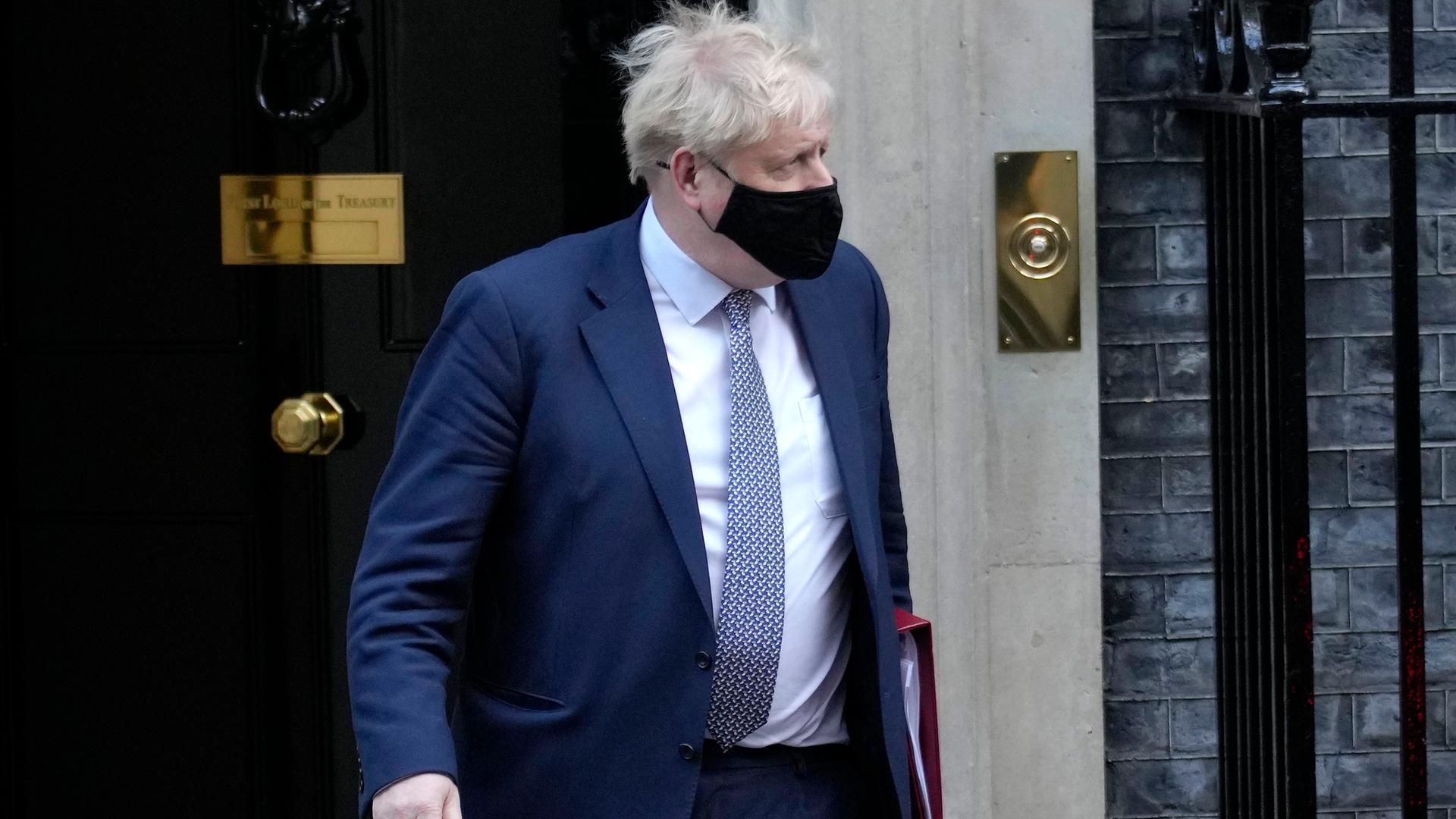 Boris Johnson mit Maske kommt aus der Haustüre der Downing Street Nr. 10