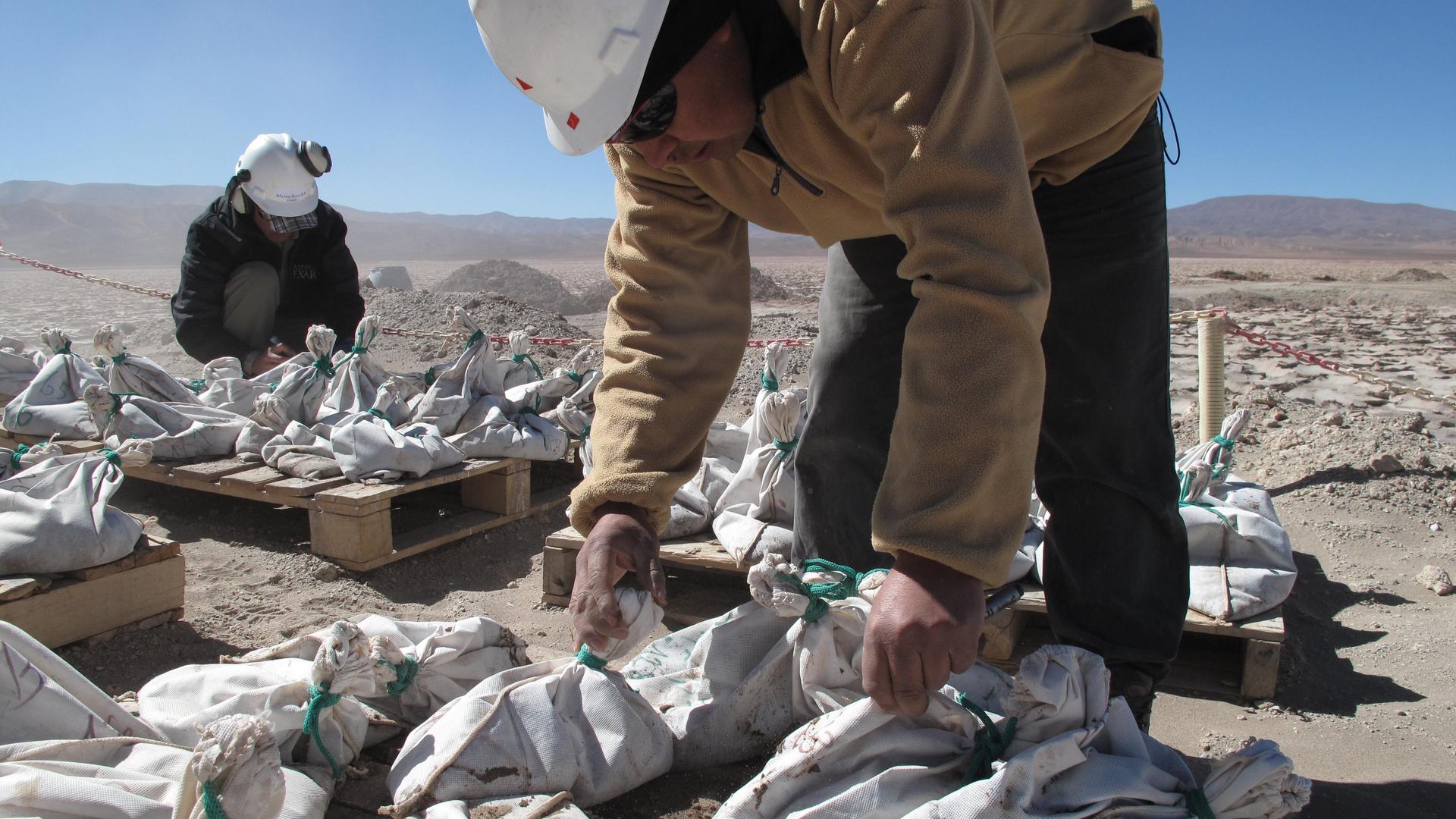 Arbeiter in einer Lithium Miene in Argentinien (Lithium Americas Corp.) mit vollen Säcken vor sich auf dem Boden. Arbeiter in einer Lithium Miene in Argentinien (Lithium Americas Corp.) mit vollen Säcken vor sich auf dem Boden.