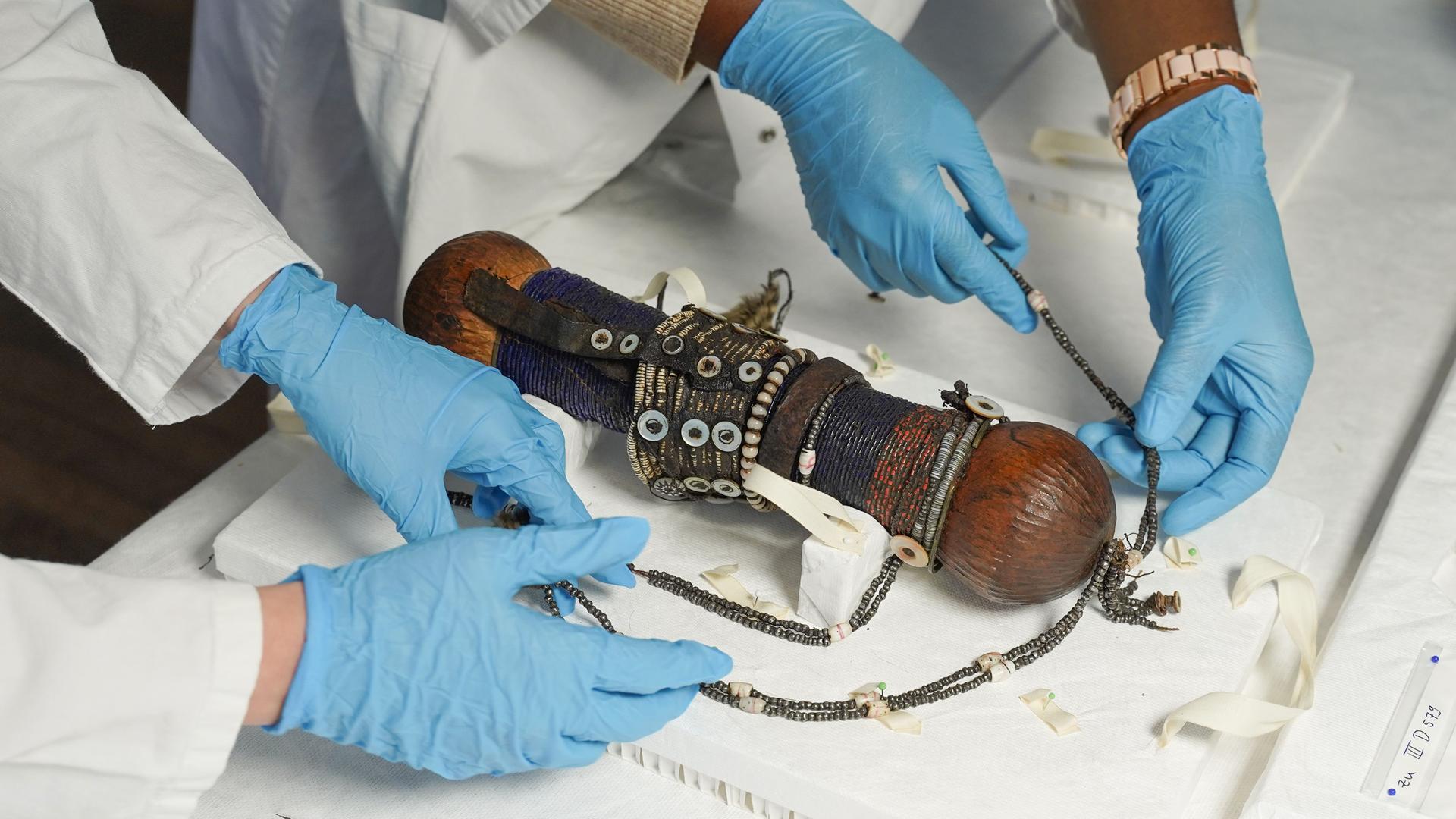 Zwei Provenienzforscherin begutachten im Ethnologischen Museum eines von 23 Objekten aus einer Sammlung, die an Namibia zurückgegeben wird. Bei dem Objekt hier handelt es sich um eine Puppe aus dem 19. Jahrhundert, die eine Fruchtbarkeitsfigur symbolisieren soll. Zwei Provenienzforscherin begutachten im Ethnologischen Museum eines von 23 Objekten aus einer Sammlung, die an Namibia zurückgegeben wird. Bei dem Objekt hier handelt es sich um eine Puppe aus dem 19. Jahrhundert, die eine Fruchtbarkeitsfigur symbolisieren soll.