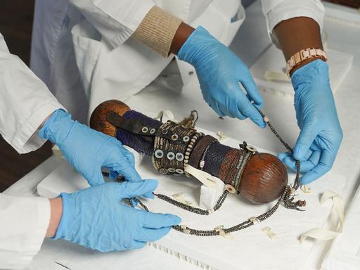 Zwei Provenienzforscherin begutachten im Ethnologischen Museum eines von 23 Objekten aus einer Sammlung, die an Namibia zurückgegeben wird. Bei dem Objekt hier handelt es sich um eine Puppe aus dem 19. Jahrhundert, die eine Fruchtbarkeitsfigur symbolisieren soll.