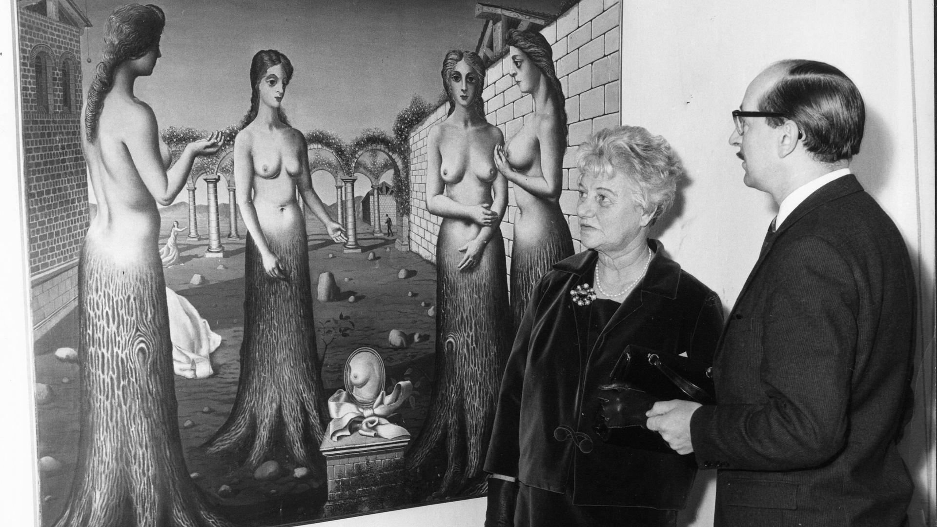 Peggy Guggenheim 1964 bei einer Ausstellung ihrer Sammlung in London mit dem Direktor der Tate Gallery, Norman Reid vor dem Gemälde "The Break of DAY von Paul Delvaux.