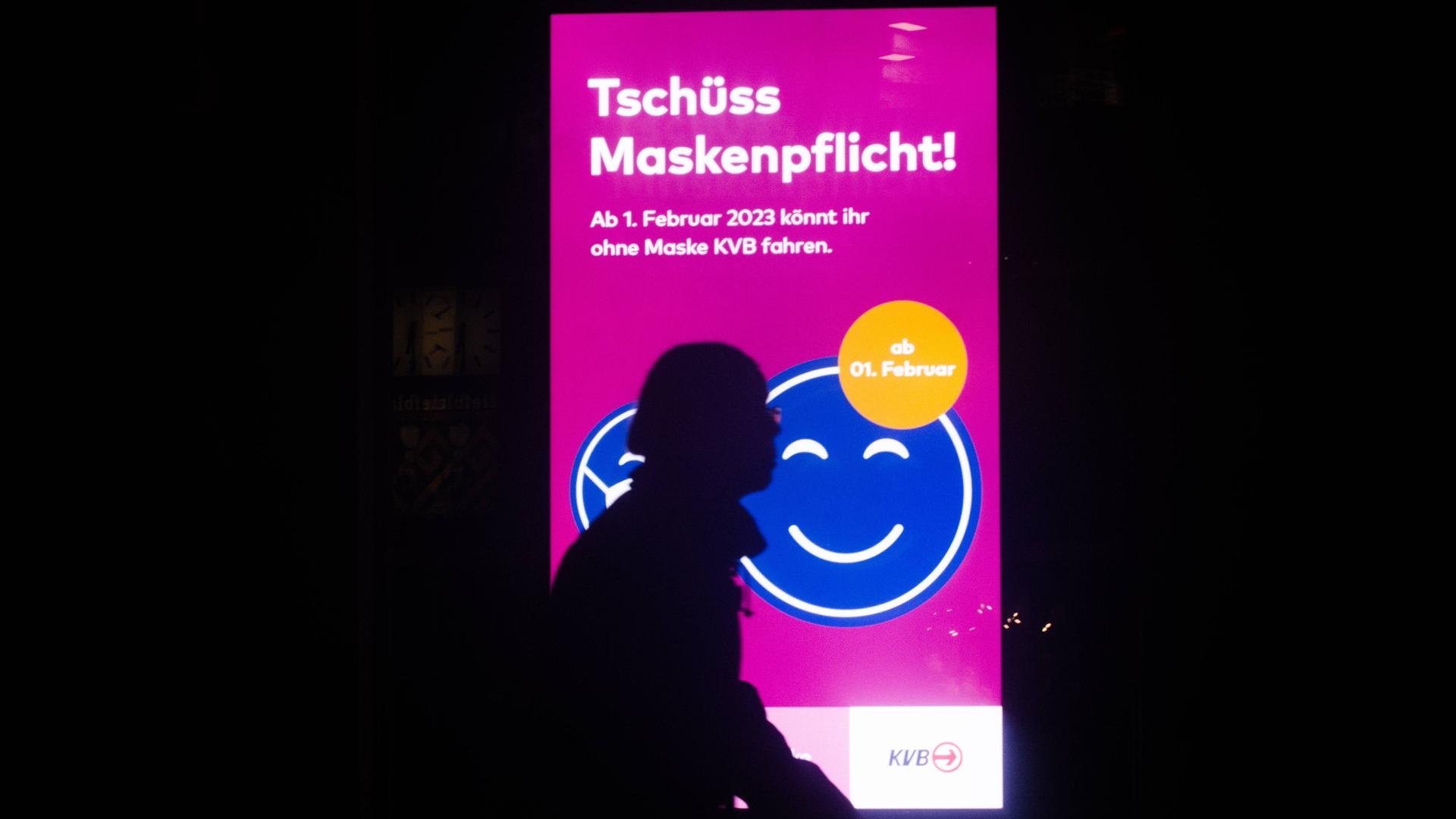 Eine Person läuft an einem Plakat vorbei, auf dem steht: Tschüss Maskenpflicht! Eine Person läuft an einem Plakat vorbei, auf dem steht: Tschüss Maskenpflicht!