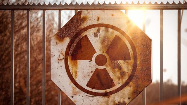 Radioaktiv Gefahr Symbol auf einem Schild an einem Zaun aus Metall, Nuklear Strahlung Warnung auf einem rostigen Schild FOTOMONTAGE