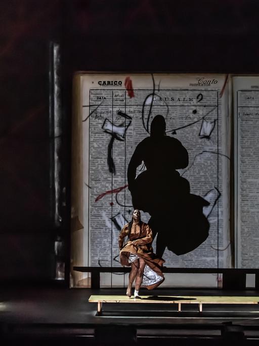 Bühnenbild mit riesigem aufgeklapptem Buch vor dem eine Tänzerin und eine Musikgruppe stehen