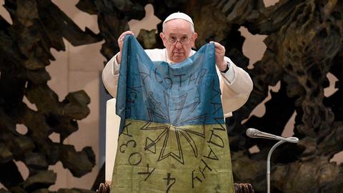 Papst Franziskus hält während einer Generalaudienz im April eine ukrainische Flagge hoch, die nach seinen Aussagen aus der ukrainischen Stadt Butscha stammt.