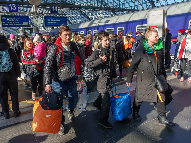 Ukrainische Flüchtlinge kommen am Berliner Hauptbahnhof an. Eine Familie geht mit Gepäck den Bahnsteig entlang.