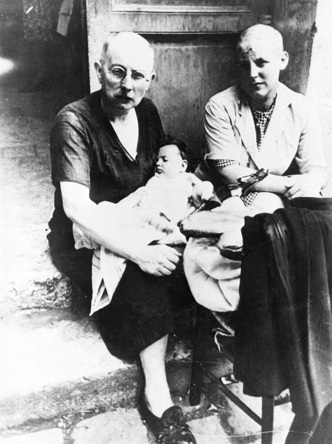 Die Schwarz-weiß-Aufnahme von 1944 zeigt zwei Frauen mit kahlgeschorenem Kopf, von denen eine einen Säugling in den Armen hält. Die Schwarz-weiß-Aufnahme von 1944 zeigt zwei Frauen mit kahlgeschorenem Kopf, von denen eine einen Säugling in den Armen hält.