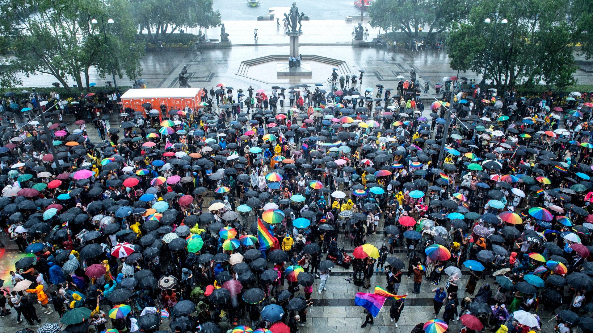 Menschen mit Fahnen und Schirmen in Regen-Boge-Farben versammeln sich in Oslo.