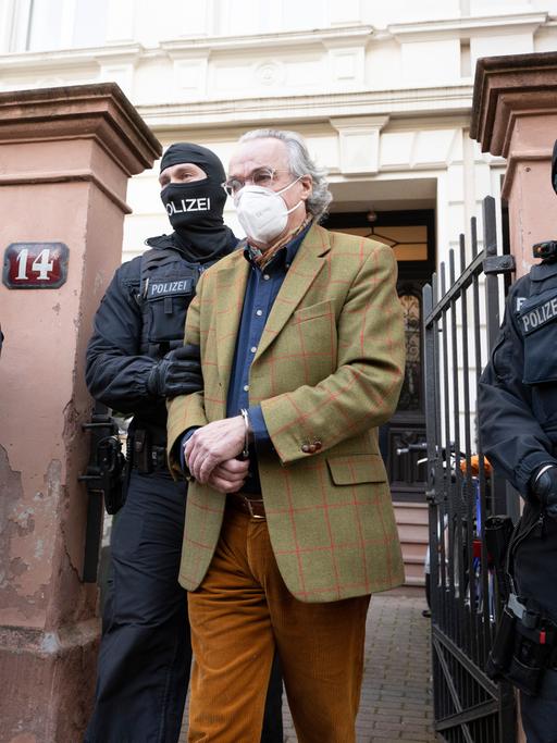 Bei einer Razzia gegen sogenannte "Reichsbürger" führen vermummte Polizisten nach der Durchsuchung eines Hauses Heinrich Reuß zu einem Polizeifahrzeug. 