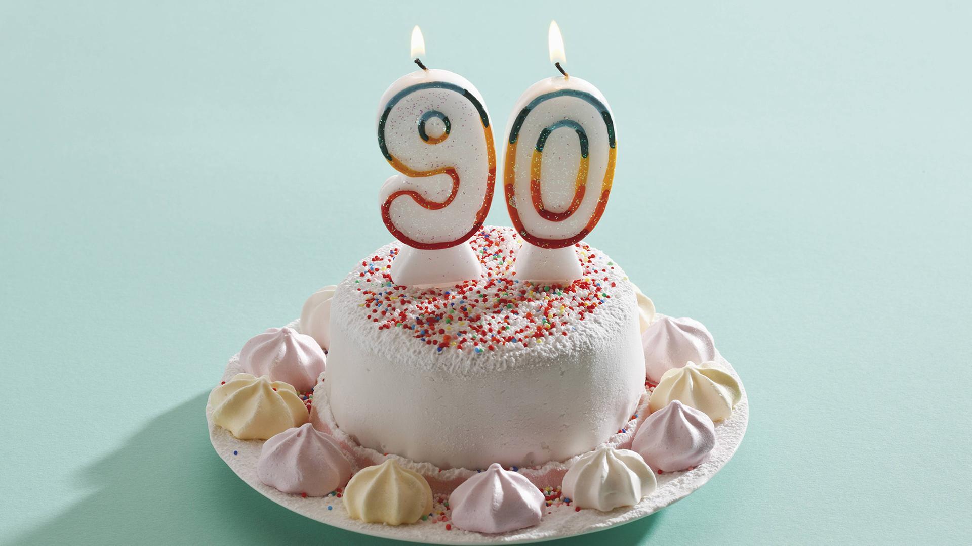 Ein Geburtstagskuchen mit zwei Kerzen, die die Zahlen 9 und 0 zeigen.