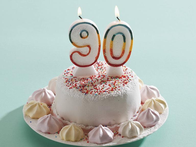 Ein Geburtstagskuchen mit zwei Kerzen, die die Zahlen 9 und 0 zeigen.