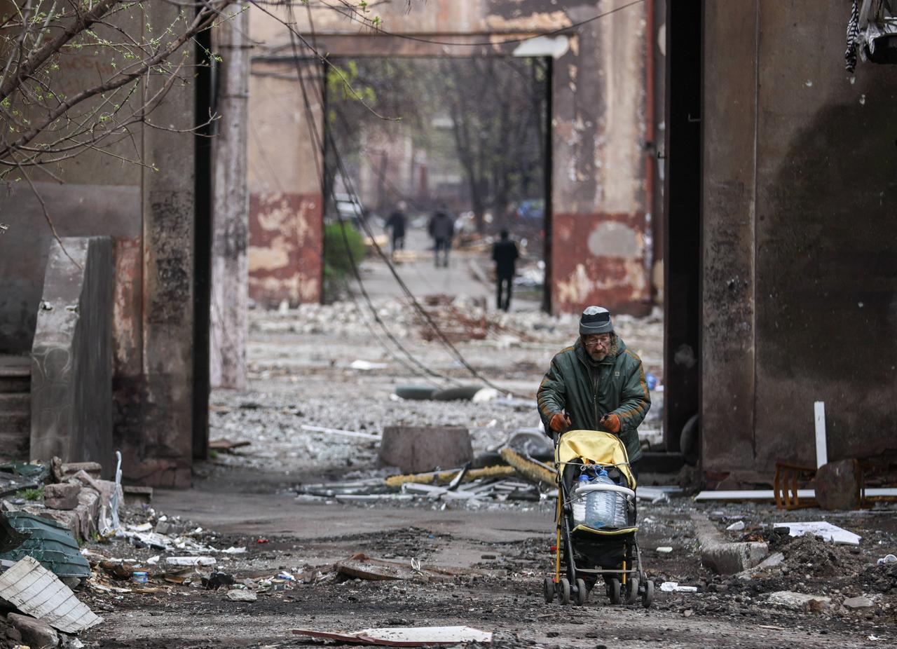 Im völlig zerstörten Mariupol schiebt ein Mann einen Kinderwagen und transportiert damit Plastikflaschen. Im völlig zerstörten Mariupol schiebt ein Mann einen Kinderwagen und transportiert damit Plastikflaschen.
