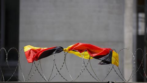 Eine Flagge der Bundesrepublik Deutschland liegt auf dem Stacheldrahtzaun einer Baustelle.