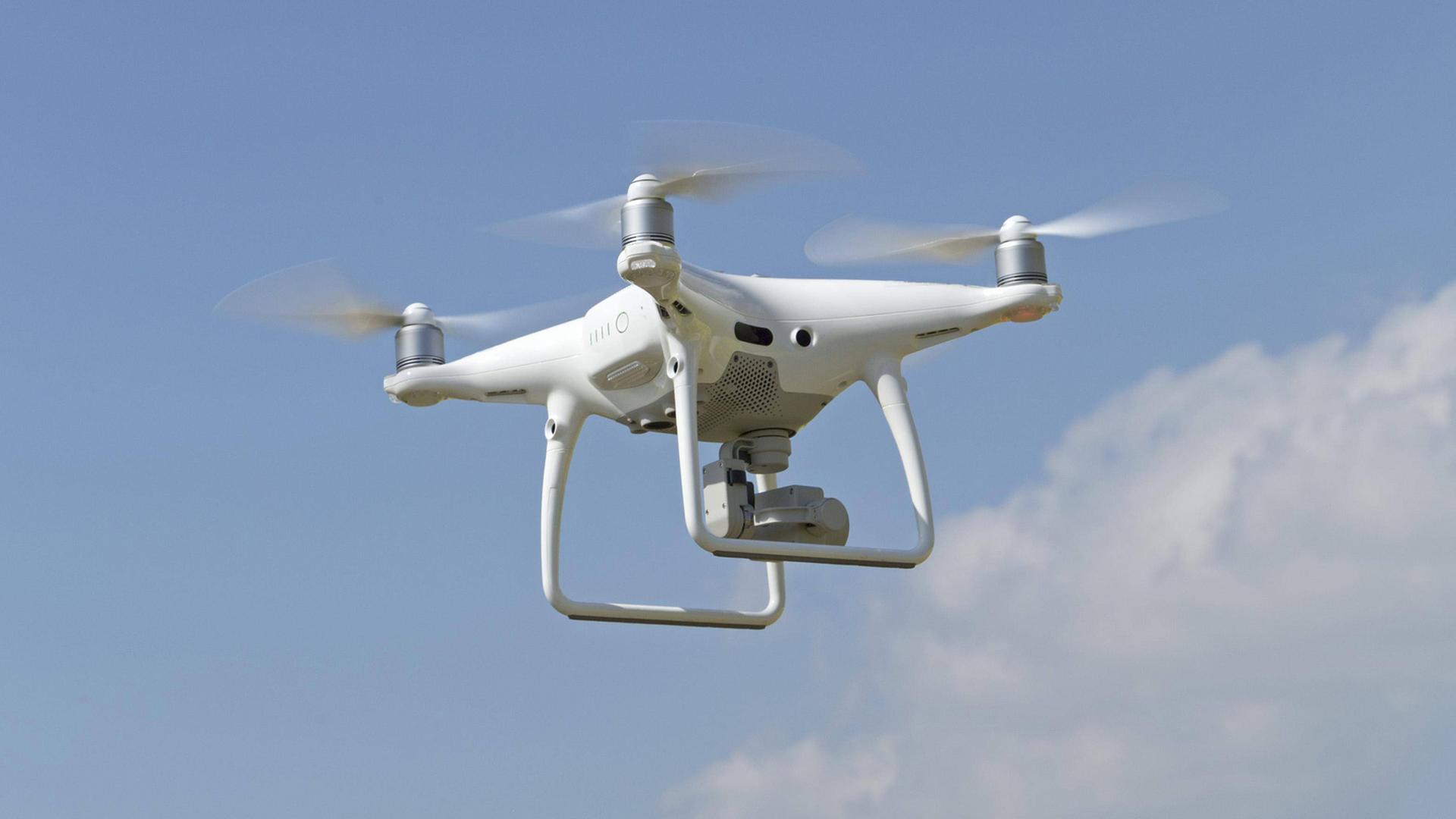 Zivile Drohnenpilotinnen in Konfliktsituation. Zu sehen: Eine fliegende Drohne mit Kamera. Zivile Drohnenpilotinnen in Konfliktsituation. Zu sehen: Eine fliegende Drohne mit Kamera.