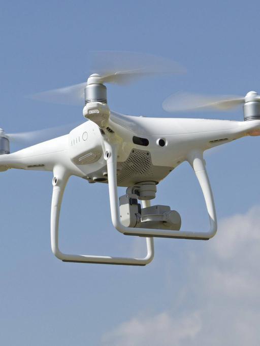 Zivile Drohnenpilotinnen in Konfliktsituation. Zu sehen: Eine fliegende Drohne mit Kamera. 