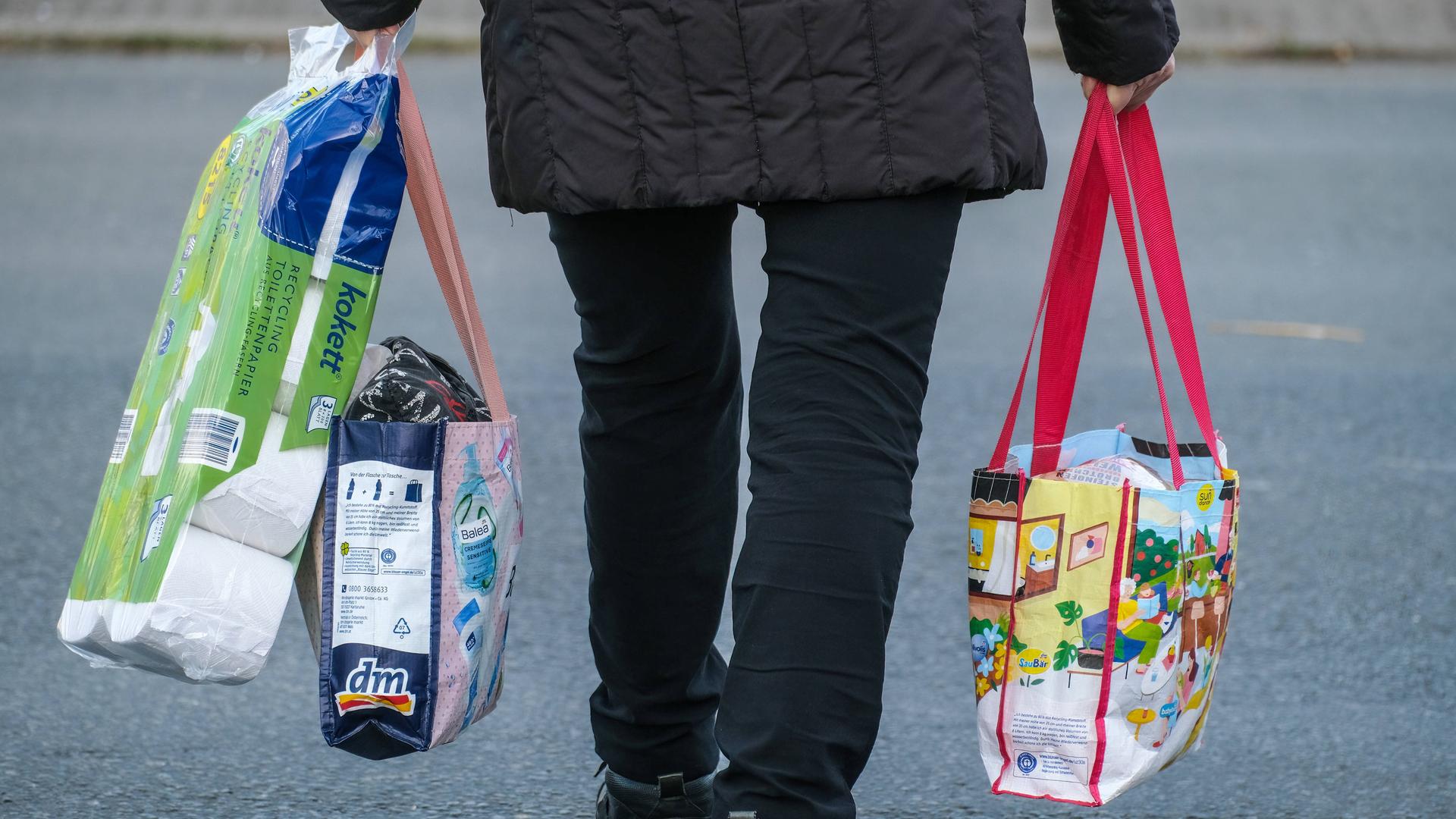 Düsseldorf 11.11.2022: Ein Mensch trägt Einkäufe in Plastiktaschen.