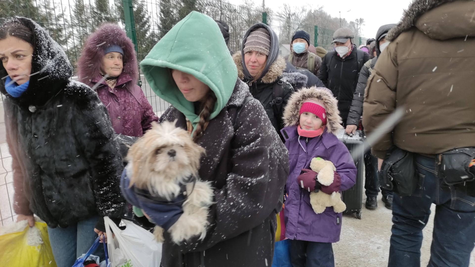 Ukrainische Flüchtlinge überqueren die Grenze zu Rumänien auf der Flucht vor dem Krieg (7.3.2022). Menschen stehen in einer Schlange vor einem Zaun