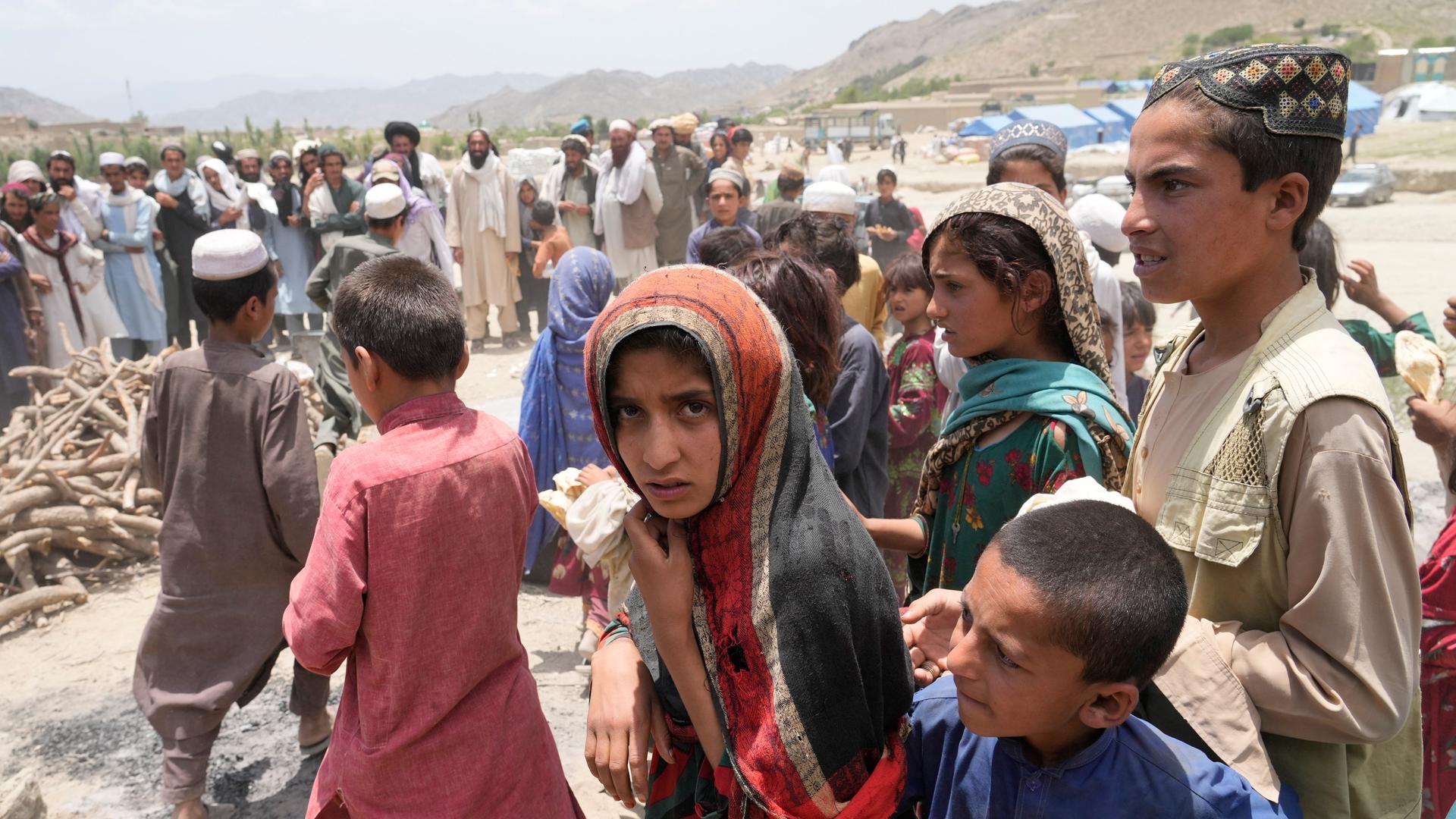 Junge Afghanen in einem Hilfscamp nach dem Erdbeben im Juni 2022: in einer Gruppe von Kindern steht in der Mitte eine junge Frau mit Kopftuch Junge Afghanen in einem Hilfscamp nach dem Erdbeben im Juni 2022: in einer Gruppe von Kindern steht in der Mitte eine junge Frau mit Kopftuch