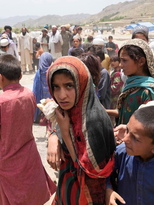 Junge Afghanen in einem Hilfscamp nach dem Erdbeben im Juni 2022: in einer Gruppe von Kindern steht in der Mitte eine junge Frau mit Kopftuch